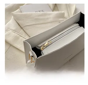 Dettaglio ravvicinato di borsa baguette bianca con cerniera dorata e scritta fashion
