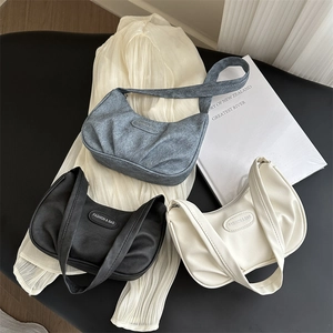 Three stylish pleated underarm bags in black, beige, and grey denim with leather tags