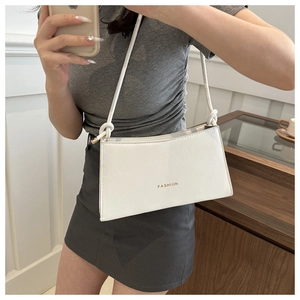 Detail of white PU leather baguette bag with gold FASHION text and knotted shoulder strap