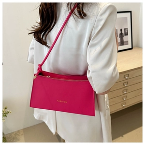 Close-up of hot pink PU leather baguette bag with gold fashion lettering and knot detail