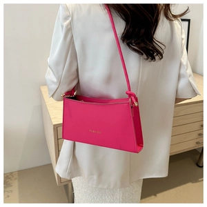 Detail of fuchsia rectangular underarm bag with gold FASHION logo and slim strap