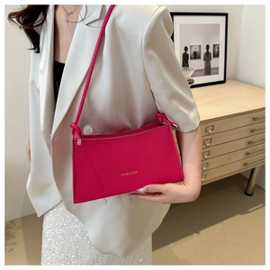 Detail of a bright magenta baguette bag with FASHION lettering and leather strap