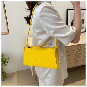Detail view of a bright yellow rectangular crossbody bag with minimalist fashion text
