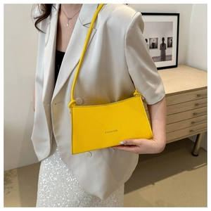 Fashionable bright yellow baguette shoulder bag with FASHION logo on a white blazer