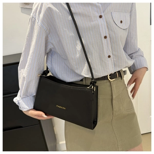 Dettaglio della scritta dorata FASHION su questa borsa sottobraccio nera minimalista