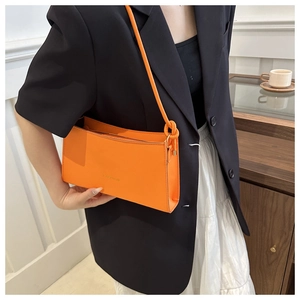 Dettaglio della borsa a spalla arancione con scritta FASHION e tracolla con nodo