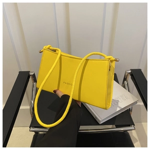 Detail of yellow baguette shoulder bag with fashion lettering and leather texture