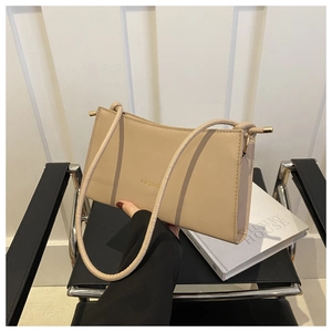 Detail of minimalist beige baguette bag with FASHION lettering on modern chair