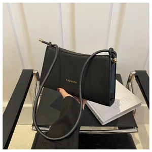 Detail of minimalist black underarm bag featuring gold FASHION lettering and metal buckle