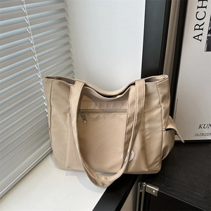 Large beige nylon tote bag with front zipper and long handles in a modern home setting