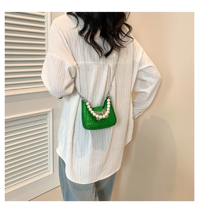 Detailed shot of green sequin mini bag with pearl handle and silver bow buckle