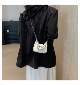 Detailed view of a white crossbody bag with pearl accents and a silver butterfly buckle