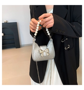 Nahaufnahme der silbernen Pailletten-Minibag mit Perlengriff und goldener Schleife