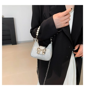 Detail of silver sequin micro bag featuring a pearl handle and gold bow clasp