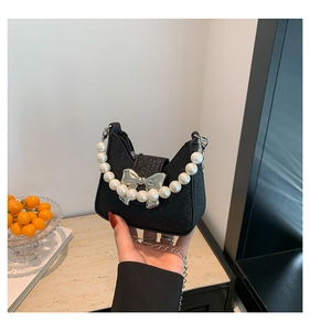 Nahaufnahme einer schwarzen Glitzer-Mini-Tasche mit Perlengriff und silberner Schleife