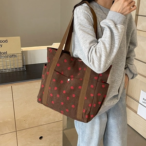 Sac fourre-tout en velours côtelé marron avec imprimé fraise porté par un mannequin