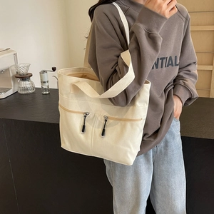 Minimalist beige canvas tote bag with dual zipper pockets and large capacity for daily use