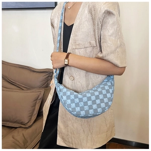 Dettaglio di una borsa hobo a scacchi blu indossata da una modella in giacca beige