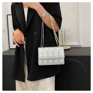 Detail of silver quilted shoulder bag with V-shaped stitching and metallic chain strap