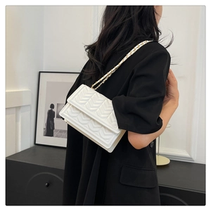 Close-up of white chevron quilted leather crossbody bag with gold-tone chain strap