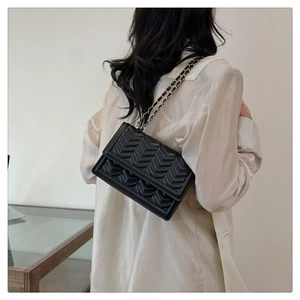 Chic quilted crossbody bag with V-shaped stitching and gold chain on model shoulder