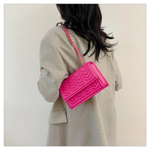 Magenta quilted shoulder bag with gold chain strap shown on model in back profile view