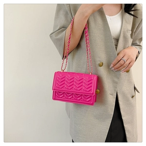 Detail of fuchsia crossbody bag with V-quilted pattern and golden chain strap