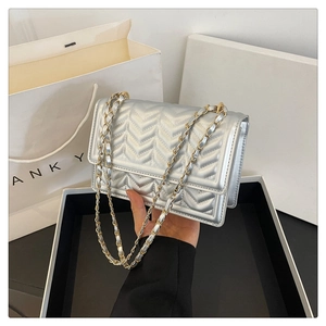 Detail of silver metallic crossbody bag with V-quilted texture and dual-tone chain strap