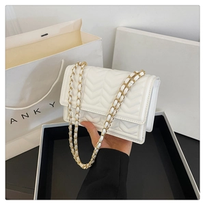 Detail of white quilted chain shoulder bag with gold hardware and V-shaped stitching