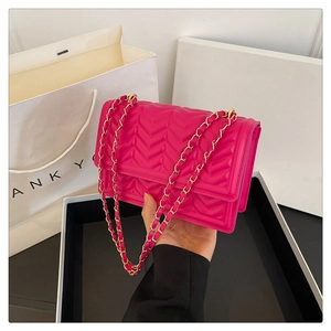 Detail of rose pink quilted chain bag featuring V-shaped stitching and gold hardware