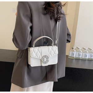Rear view of a model wearing the white quilted crossbody bag with crystal buckle and chain
