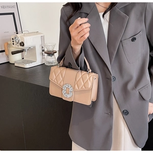 Close-up of beige quilted crossbody bag with luxury rhinestone buckle in a cafe setting