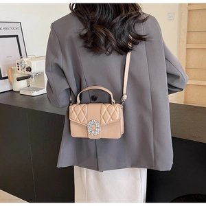 Brown quilted crossbody bag with diamond buckle shown on a model in a grey suit
