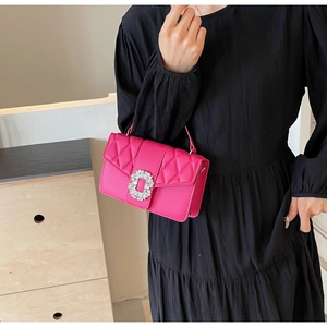 Detail of rose red quilted crossbody bag with luxury rhinestone buckle on black dress