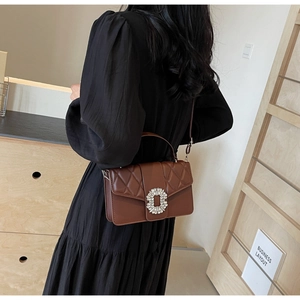 Detail of coffee brown quilted crossbody bag with large rhinestone buckle on side view