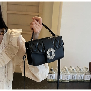 Detail of black quilted crossbody bag featuring a large sparkling crystal buckle