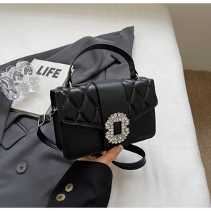 Close-up of black quilted handbag featuring a sparkling rhinestone square buckle detail