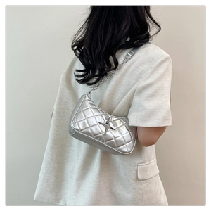 Silver metallic quilted shoulder bag with star charm worn by a model in Y2K style