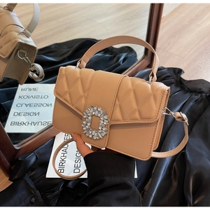 Detail of quilted beige leather handbag featuring a large rectangular crystal buckle