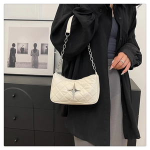 Detail of white quilted underarm bag featuring a silver star metal emblem and chain strap