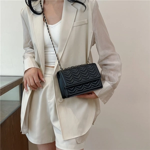 Classic black quilted crossbody bag with golden chain strap on a stylish woman