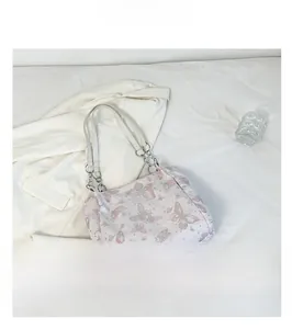Dettaglio borsa rosa con stampa a farfalla, catena argentata e manico bianco