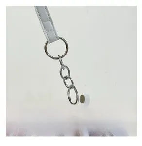 Dettaglio della catena d'argento e del cinturino in pelle bianca sulla borsa tote