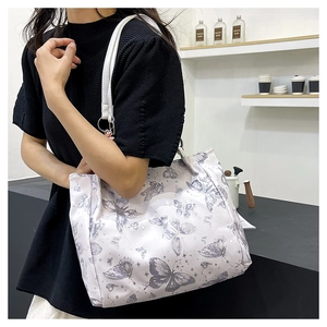 Dettaglio della borsa tote bianca con stampe di farfalle viola e tracolla in pelle bianca