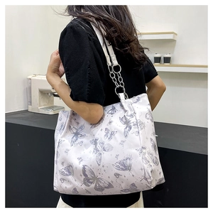 Dettaglio della borsa tote bianca con stampa farfalla viola e tracolla in pelle a catena