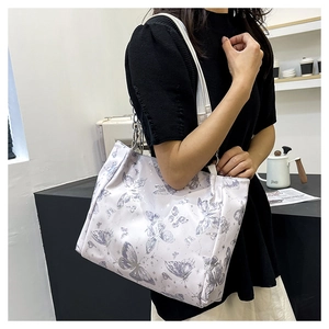 Dettaglio della borsa tote bianca con stampe di farfalle viola e catena in metallo argento