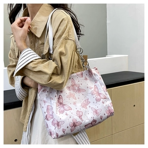 Dettaglio della borsa shopper bianca con stampe di farfalle rosa e catena in metallo