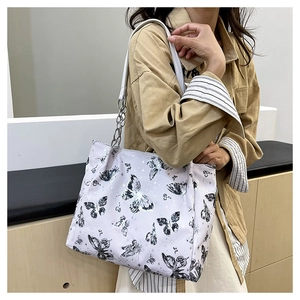 Dettaglio della grande borsa tote con stampe farfalle e tracolla a catena