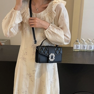Quilted black leather shoulder bag with crystal buckle shown on a floral dress model