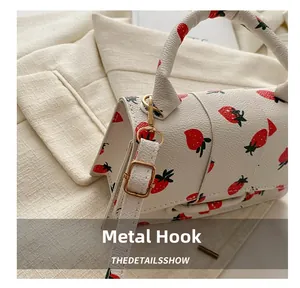 Detail van aardbeien mini-tas met gouden hardware haak en getextureerd PU-leer kunst